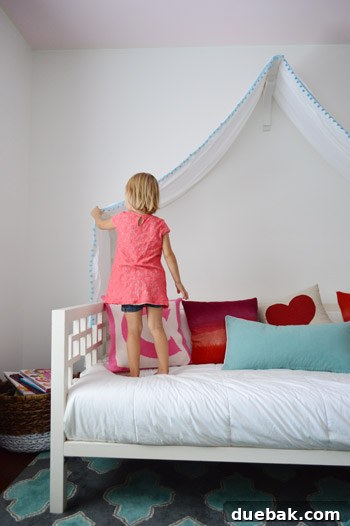 Clara happily interacting with her new bed canopy, reaching up to touch the fabric