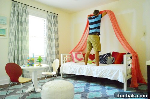 A person holding up a piece of white fabric to visualize a bed canopy