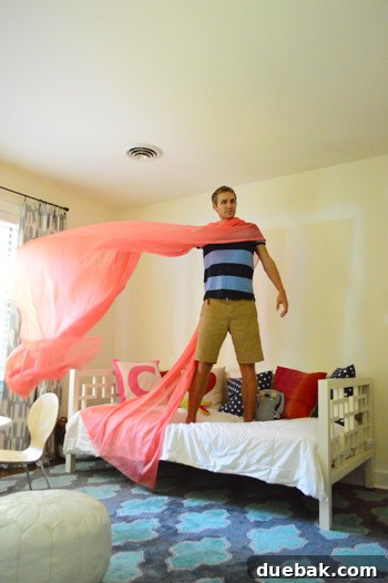 A person playfully draped in white sheer fabric, simulating a canopy
