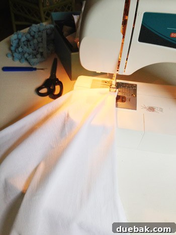 Sewing machine in action, hemming the edge of the white fabric