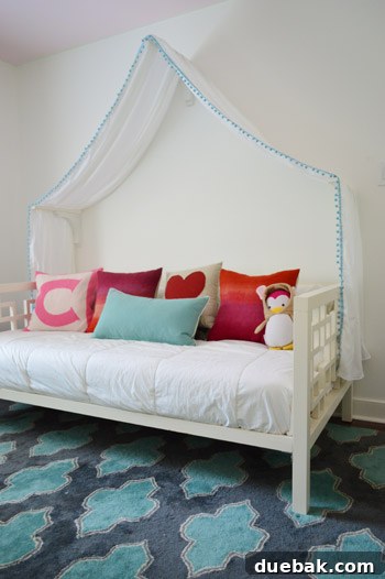 Finished white bed canopy with turquoise pom-pom trim, draped over a child's bed