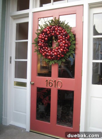 Layered Christmas Wreath Front Door A front door with a unique layered wreath featuring a red ornament wreath over a fresh fir wreath in Richmond.