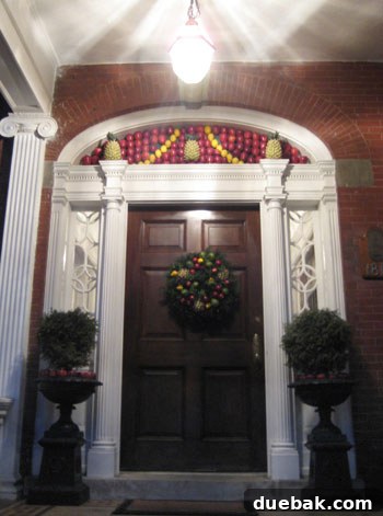 Fresh Fruit Christmas Door Decor A unique holiday door decoration featuring an arch of fresh fruit (apples, lemons, pineapples) on a green foam base.