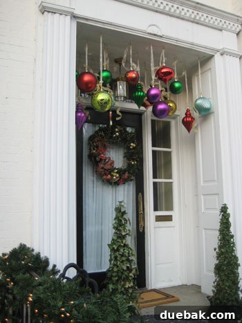 Suspended Ornaments Porch Decor A front porch decorated with numerous oversized Christmas ornaments suspended by ribbons from the ceiling, creating a playful holiday look.