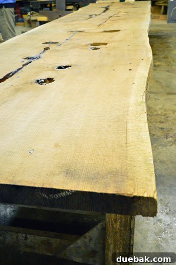 Signature Showhome Designs 6 A large, unfinished raw-edge wood slab on sawhorses, destined to become a custom breakfast table.
