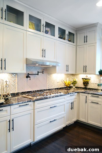 Close-up of soft gray kitchen cabinets with striking dark hardware