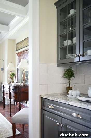 Butler's pantry with dark gray cabinets connecting kitchen and dining room