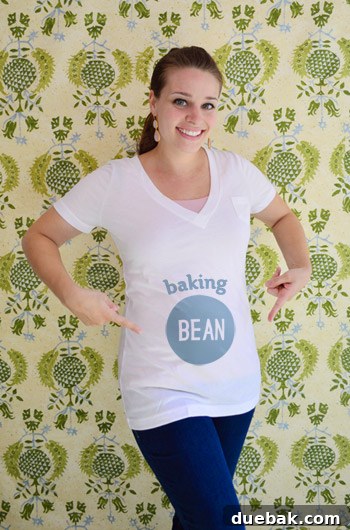 Sherry, smiling brightly, gently cradling her baby bump, showcasing the early stages of her pregnancy.