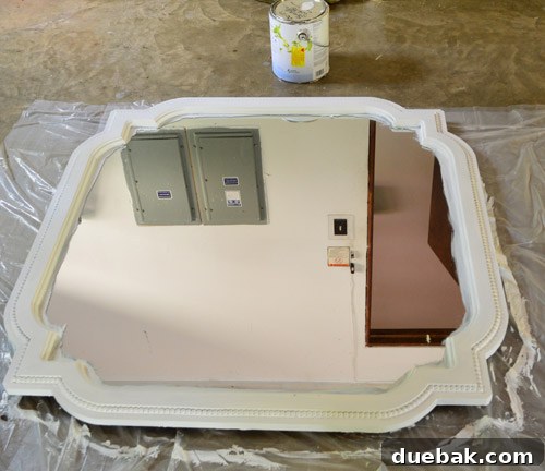 Sherry painting the quatrefoil mirror white on a dropcloth in the garage