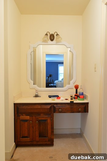 The newly painted mirror looking cramped above the vanity with the existing light fixture