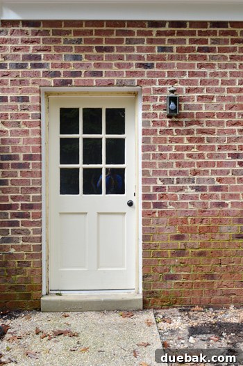 Old, small exterior light fixture on green brick wall