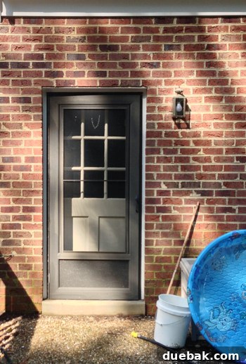 Worn back door with damaged trim and a small, old light