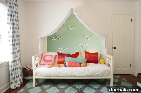 Photoshop mockup: Clara's room with a blue-gray wall featuring a friendly giraffe or zebra peeking above the canopy.