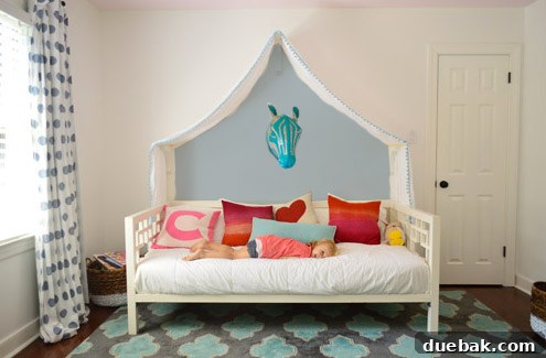 Photoshop mockup: Clara's room with a wall design featuring colorful teardrop shapes in various hues above the canopy.