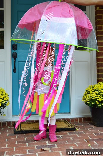 Clara, the Fairy Queen of the Jellyfish, proudly showing off her DIY costume with a clear umbrella, pink tissue paper, and LED lights.