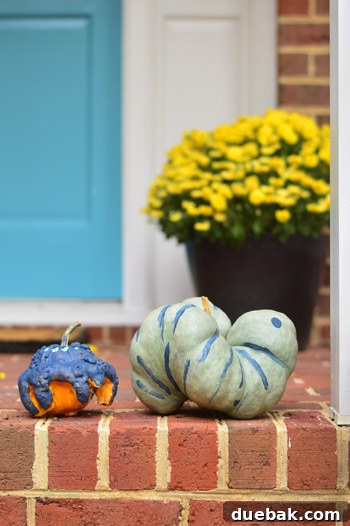 Clara standing proudly next to her painted spider pumpkin and a caterpillar pumpkin.