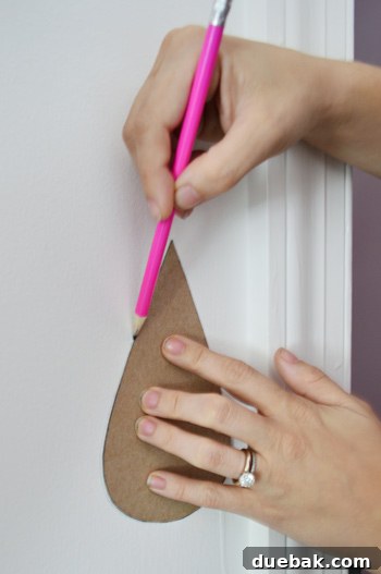 Tracing Raindrops On Wall With Pencil using Cardboard Template Shape - Hand tracing raindrop shapes onto a wall using a custom cardboard stencil and a pencil.