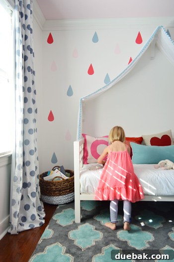 Girl Playing On Bed Under Final Raindrop Mural Over Fabric Canopy Bed - A happy girl playing on her bed under the newly painted colorful raindrop mural and fabric canopy.