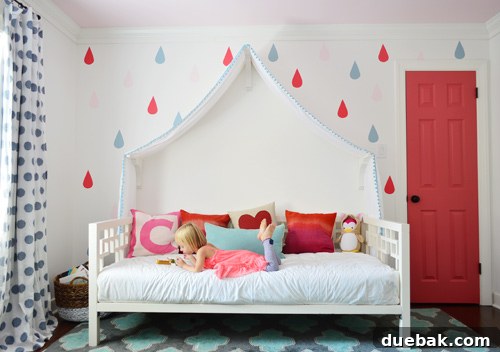 After Photo Of Girl Reading On Daybed With Fabric Canopy And Colorful Door And Raindrop Mural - A girl happily reading on a daybed with a new colorful raindrop mural and a bright pink closet door.