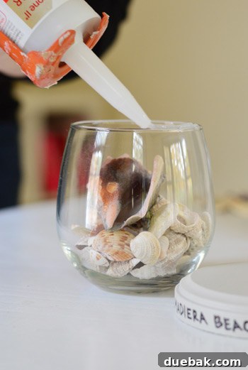 Applying clear silicone caulk to the rim of a stemless wine glass