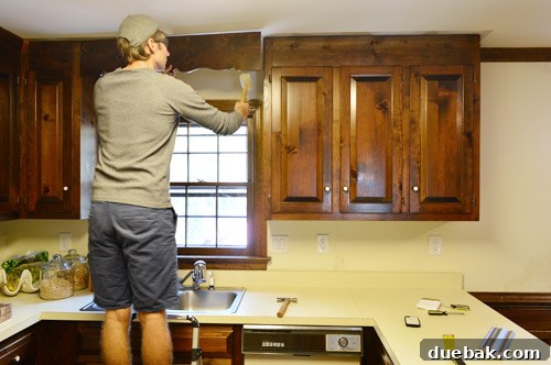 How to Remove and Rehang Kitchen Cabinets 4 DIYer prying off crown molding above kitchen cabinets