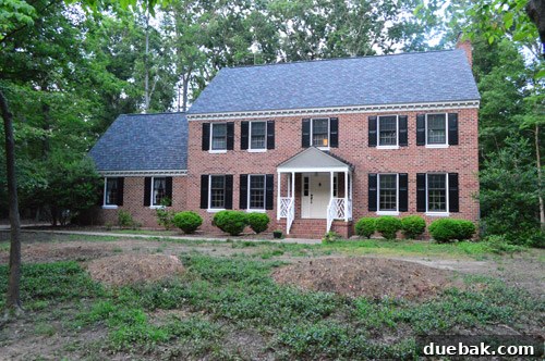 Curb Appeal Mastery 2 Before image of an uneven front yard with tree stump piles