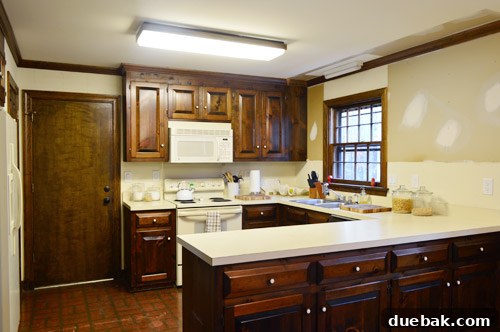 The kitchen with old curtains, wallpaper, and outdated appliances, awaiting a multi-phase renovation.