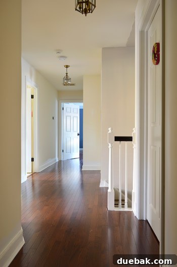 The upstairs hallway with old carpeting, blue trim, and brass hardware, nearing completion with new hardwoods.