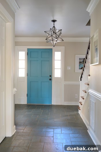 The foyer of our house, showing blue trim, wallpaper, and an old light, awaiting a modern update.