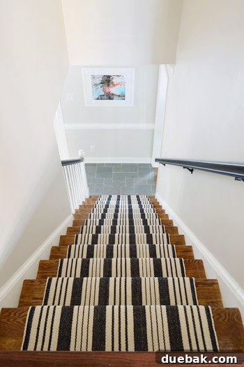 The staircase in our home, showing bare wood, blue spindles, and a runner, nearly complete.