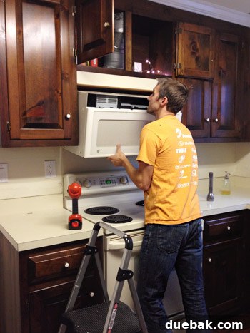 Serene Blue-Gray for Kitchen Walls 8 John providing support from below as a heavy over-the-range microwave is being detached, ensuring a safe removal process.
