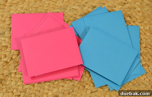Family members holding pink and blue envelopes during a gender reveal