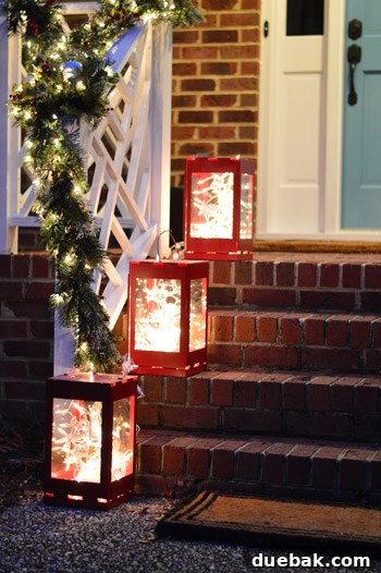 Effortless Window Wreath Styling 15 A beautiful array of red lanterns, each aglow with twinkling fairy lights, strategically placed on alternating steps leading up to the porch, creating a magical and inviting pathway for holiday visitors.