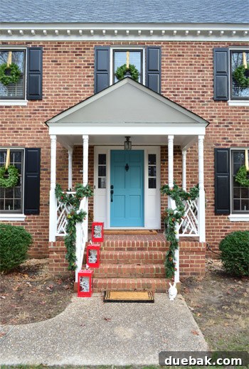 Effortless Window Wreath Styling 17 The charmingly decorated house exterior captured in daylight, showcasing the elegant Christmas wreaths, festive garland, and red lanterns in their full, unlit glory.