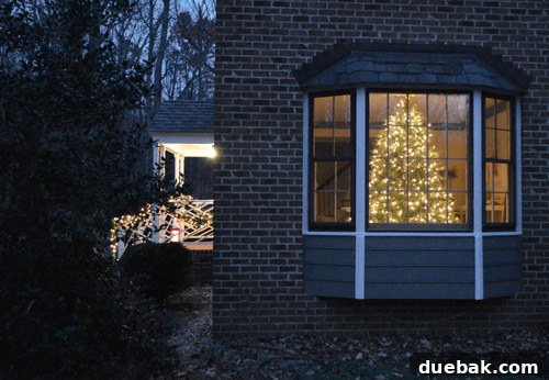 Effortless Window Wreath Styling 5 Our house exterior, adorned with beautiful Christmas wreaths and other decorations, with a peek of the yet-to-be-decorated indoor Christmas tree visible through the inviting bay window.