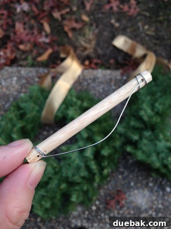 Effortless Window Wreath Styling 10 A close-up view of a custom-made DIY 'trapeze thing,' crafted from a small wooden dowel with wire strung through, specifically designed to keep wreath ribbons flat and neat.