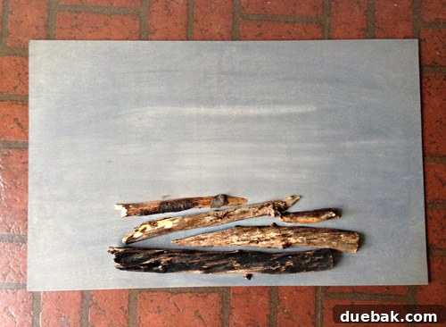 Get Crafting 4 DIY Holiday Decorations 6 Cut tree branches stacked on gray stained plywood sheet for DIY holiday faux fireplace