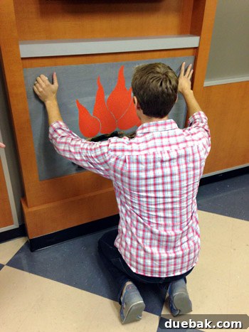 Get Crafting 4 DIY Holiday Decorations 9 John placing fake fireplace DIY onto mantle in childrens hospital waiting room