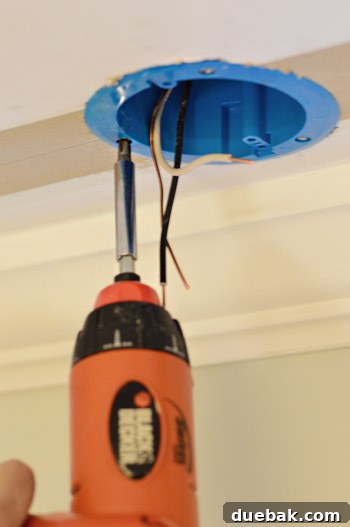 Upgrade Your Lighting: Swapping Fluorescent Fixtures for Pendants 18 Securing old work electrical fixture box with screwdriver