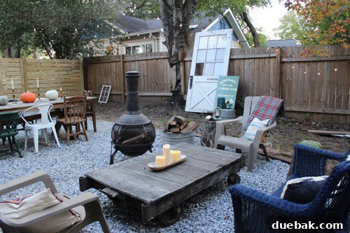 Outdoor gathering area with a wicker sofa, chiminea, and an antique factory cart coffee table.