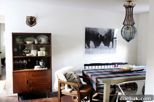 Dining area showcasing eclectic chairs, a woven chandelier, and a large buffalo art piece.