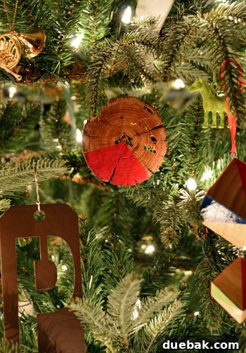 Rustic Wood Slice Christmas Creations 15 Close-up of a red painted wood slice ornament hanging on a Christmas tree