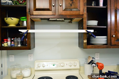Replacing an Over-the-Range Microwave with a Range Hood 9 A wooden board clamped across a cabinet opening, supporting the range hood during installation