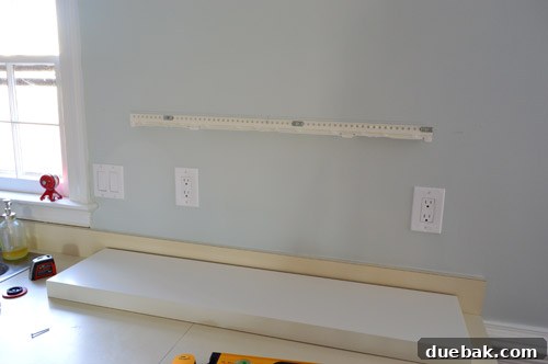 Metal bracket securely screwed to the kitchen wall, ready for the placement of the IKEA floating shelf, showing precise attachment points.