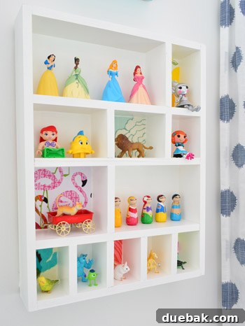 Clara happily interacting with her new white wooden figurine cubby shelf mounted on the wall, filled with her tiny toy figures.