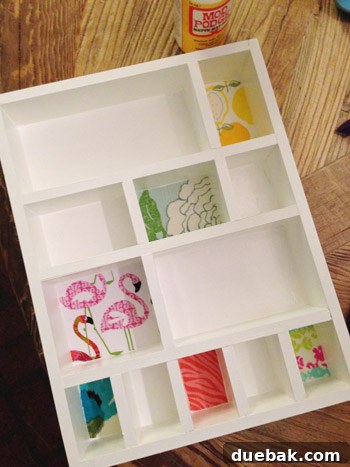 A hand carefully pressing a piece of fabric into a cubby of the wooden shelf, using Mod Podge for adhesion.