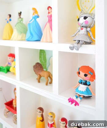 Close-up of Clara's tiny hands gently placing a small animal figurine into a cubby of the new display shelf.