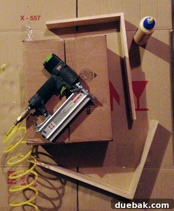 Close-up of wooden pieces being assembled with wood glue and brad nails, forming a corner of the shelf frame.
