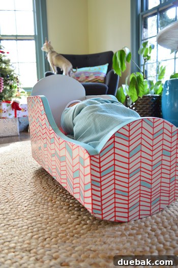 Close-up of a wooden cradle with a newly painted geometric pattern in red, blue, and white.