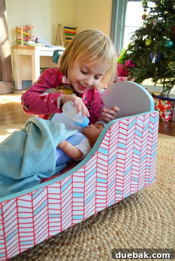 Clara happily interacting with her newly painted, geometric pattern cradle during Christmas Eve.